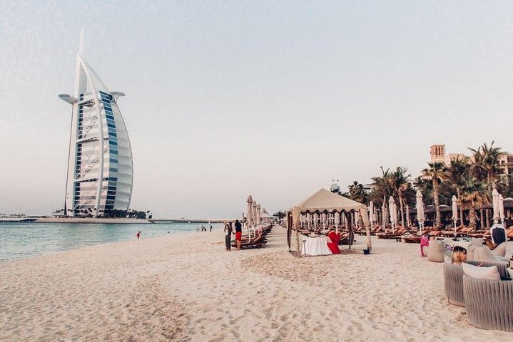 Experience the stunning blend of modern architecture and serene beachfront in Dubai where the iconic Burj Al Arab stands proudly against the backdrop of gentle waves and palm trees.